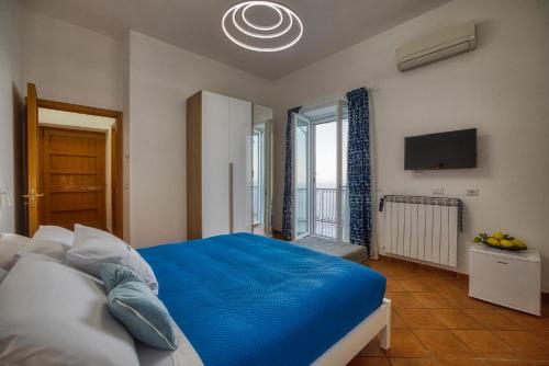 a bedroom with a blue bed and a television at Rosy's Room in Furore