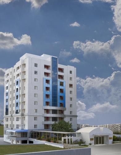 a tall white building with a blue at Royal Orchid Golden Suites Pune in Pune