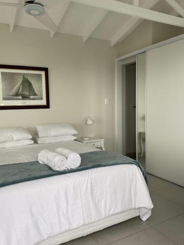 a bedroom with a white bed with towels on it at Martin's Cottage in Great Brak River