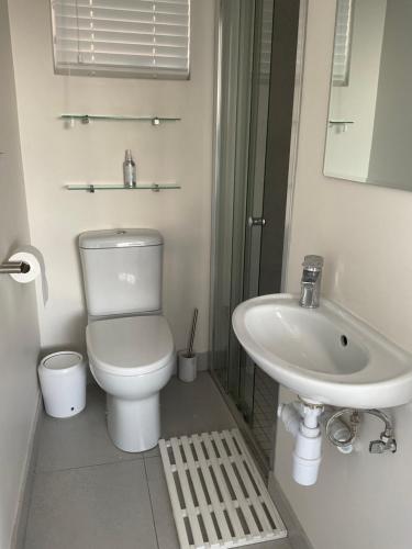 a white bathroom with a toilet and a sink at Martin's Cottage in Great Brak River