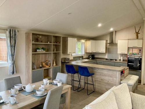 cocina con mesa de madera y sillas azules en Rambells Lodge, en Warton
