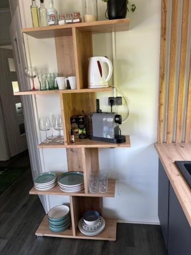 a kitchen with wooden shelves with dishes and a toaster at rishko resort - Lake View - Private Sauna - free Parking - 24hr Self chceck-in in Holčíkovce