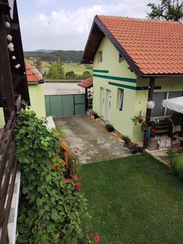 a yellow house with a red roof and a yard at Srebrna dolina in Kremna