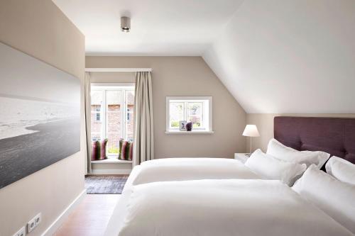 a bedroom with two white beds and a window at Rungholt in Oevenum