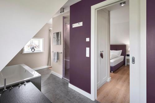a bathroom with a purple wall next to a bed at Rungholt in Oevenum