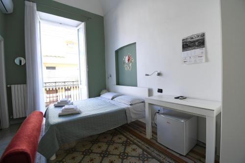 a bedroom with a bed and a desk and a window at La Dimora dell' Architetto in Gravina in Puglia