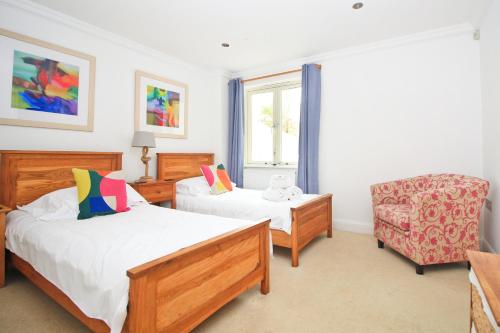 ein Schlafzimmer mit zwei Betten, einem Stuhl und einem Fenster in der Unterkunft BEACHSIDE SPACIOUS apartment, private garden in Saint Merryn