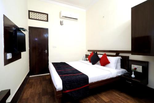 a bedroom with a white bed with red pillows at TRPOTELS Town Inn in Gwalior