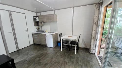 a small kitchen with a table and chairs in a room at L’Orée du Bois by Noricamp in Arthez-de-Béarn