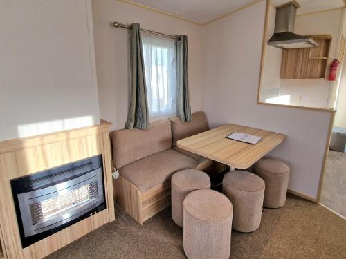 a living room with a table and a chair and a tv at Summer Breeze Getaway, West Sands in Selsey