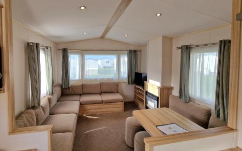 a living room with a couch and a table at Summer Breeze Getaway, West Sands in Selsey