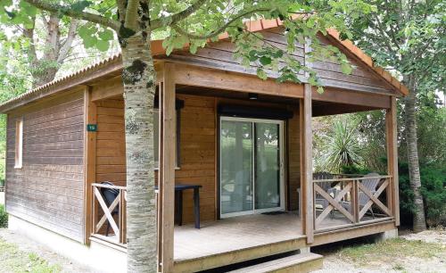 a small wooden cabin with a porch and a door at L’Orée du Bois by Noricamp in Arthez-de-Béarn