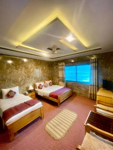 a bedroom with two beds and a large window at Blangsa Indus View Hotel in Skardu