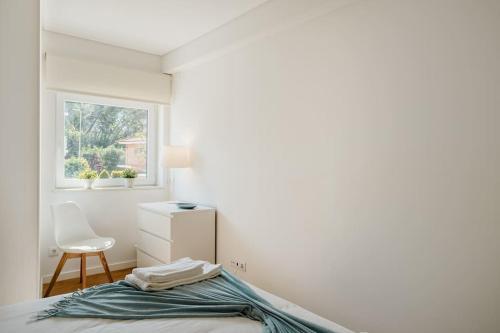 a bedroom with a bed and a chair and a window at Villa Miramar - Seaside Cascais in Cascais