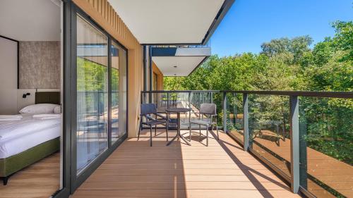 a bedroom and a balcony with a bed and a table at Apartamenty Helski Brzeg in Hel