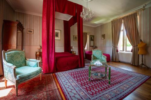 a living room with a red bed and two chairs at Le Moulin de Francueil in Francueil