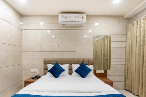a bedroom with a bed with blue pillows at Hotel Noble Inn, Ahmedabad in Ahmedabad