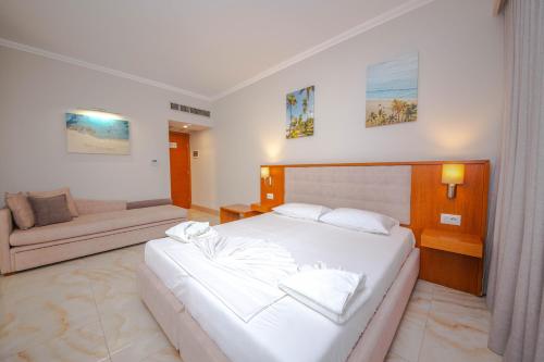 a bedroom with a large white bed and a couch at Hotel Sole Mare in Ksamil