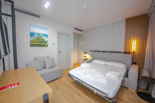 a bedroom with a white bed and a couch at Hotel Sole Mare in Ksamil