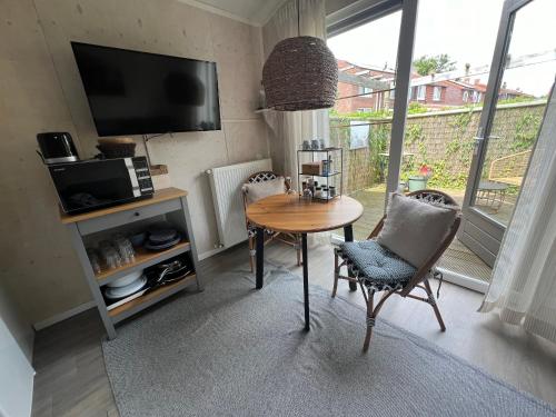 a living room with a table and chairs and a television at Studio Bluuven in Scharendijke