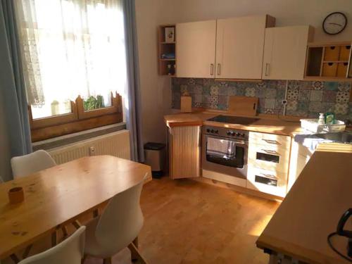 a kitchen with white cabinets and a wooden table and a table and chairs at Forsthaus Nicolai in Pretzsch