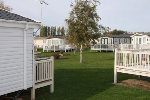 a row of houses in a yard with a white fence at Place2bee,Family & Pet Friendly 6 Berth Caravan, Manor Park Hunstanton in Hunstanton