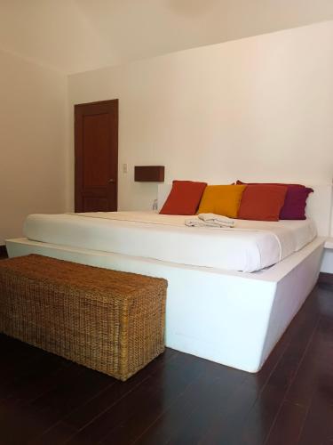 a bedroom with a large white bed and a wicker stool at Villa Kalachuchi V.K in Puerto Princesa City