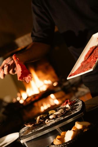 a person holding a slice of pizza over a fire at Le Cedrus Hotel in Al Arz