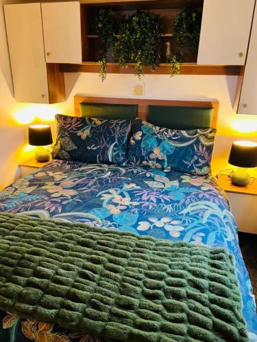 a bedroom with a bed with a blue comforter and two lamps at Place2bee,Family & Pet Friendly 6 Berth Caravan, Manor Park Hunstanton in Hunstanton