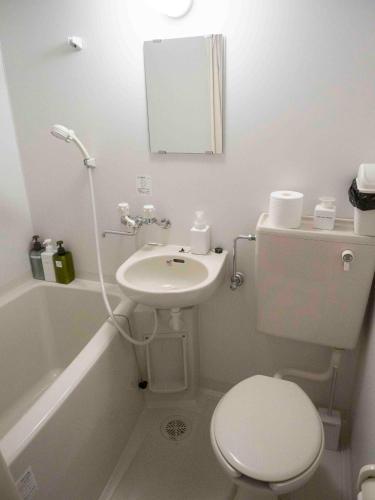 Un baño con un inodoro blanco y un lavabo. en GuestHouse Hostel MangeTak ゲストハウス マングタック広島, en Hiroshima