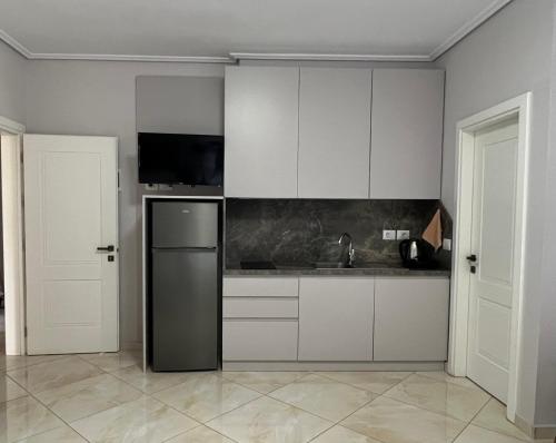 a kitchen with white cabinets and a stainless steel refrigerator at Prestige Home KSAMIL in Ksamil