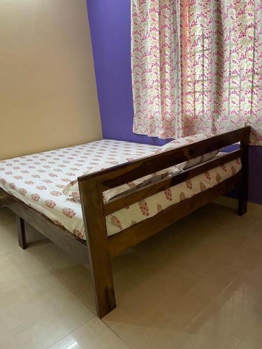 a wooden bed in a room next to a window at Krishna Homestay 2BHK apartment in Chennai