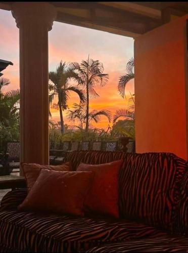a couch in a room with a painting of palm trees at RoofTop Boutique Hotel Adults Only in Serekunda