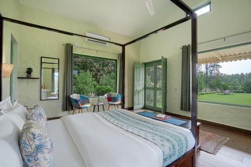 a bedroom with a bed and a large window at SaffronStays Dalewal Jungle Lodge, Hoshiarpur in Hoshiārpur