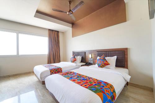 a bedroom with two beds and a ceiling fan at Oriva Nestlay Rooms Ramnad - Nr Golden Shopping Mall in Rāmanāthapuram