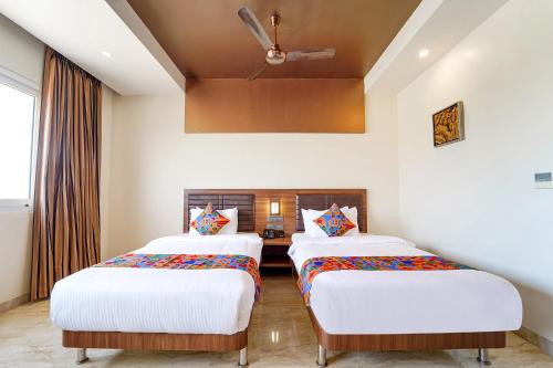 two beds in a room with white walls at Oriva Nestlay Rooms Ramnad - Nr Golden Shopping Mall in Rāmanāthapuram
