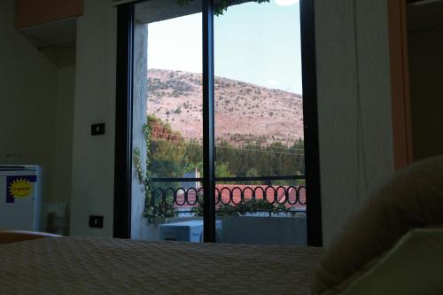 a bedroom with a window with a view of a mountain at Hotel and Restaurant Shallalat Anjar in ‘Anjar