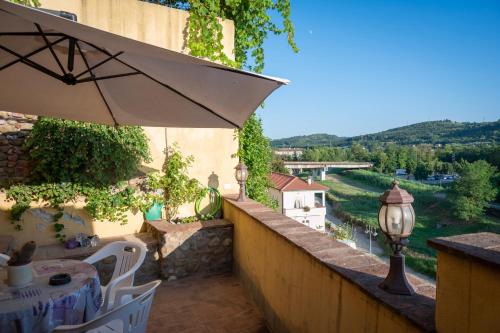 a balcony with an umbrella and a table and chairs at Appartamento rustico con vista in Montelupo Fiorentino