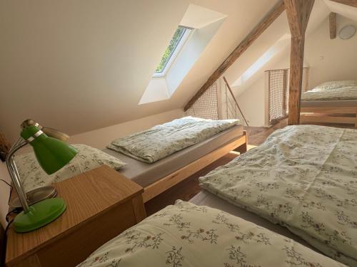 a bedroom with two beds and a lamp on a table at Tkalcovna U Zlatého potoka in Dobřany