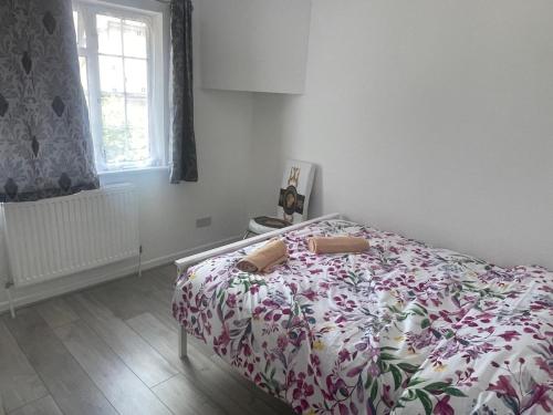 a bedroom with a bed with a floral bedspread at Baraka Edgware in Stone Grove