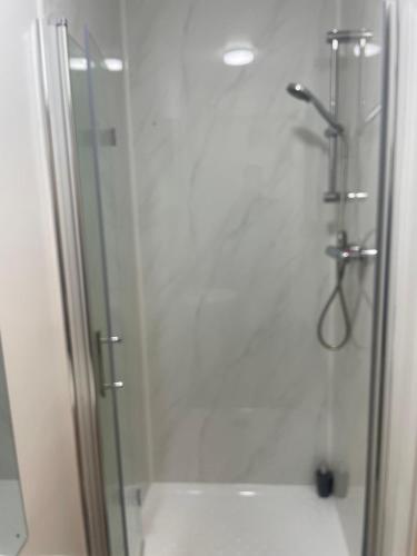 a bathroom with a shower with a glass door at Baraka Edgware in Stone Grove