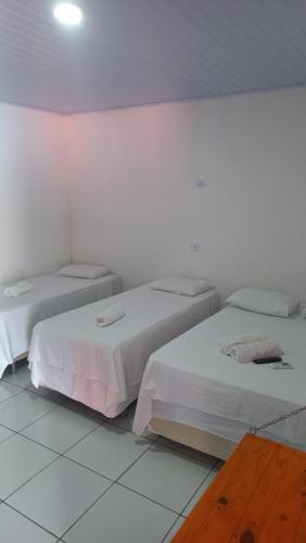 two beds in a room with white walls at Pousada Lençóis do Delta in Tutóia