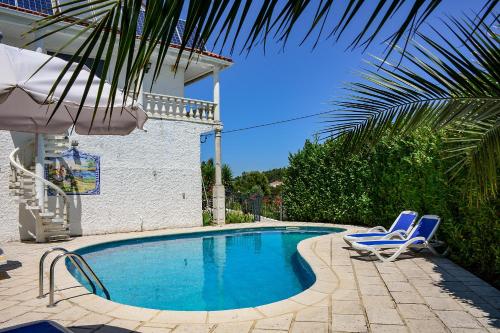 a swimming pool with two chairs and an umbrella at Villa Casa da Rosa, com piscina privada in Carvalheira Grande