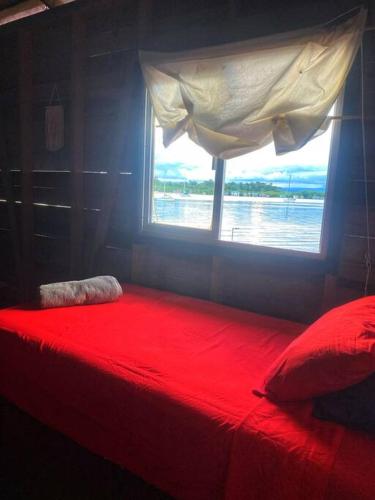 a red bed in a room with a window at Oceanfront, Quiete and Convenient Location in Bocas del Toro