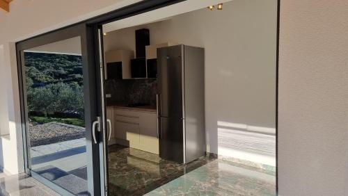 Una cocina con puerta corrediza de vidrio con refrigerador. en Robinson house DUJE, en Pašman