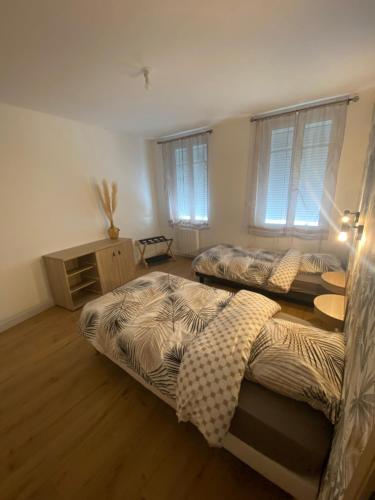 two beds in a room with wooden floors and windows at Welc'Home in Saint-Valéry-en-Caux
