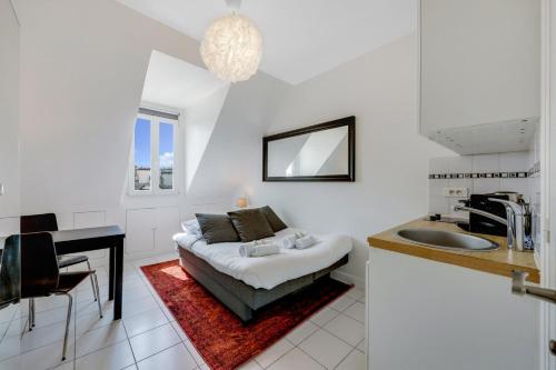 Cette chambre blanche comprend un lit et un lavabo. dans l'établissement Paris Marais Rosiers, à Paris