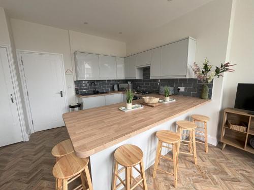 a kitchen with a wooden counter top and stools at Holywell Stays in Old Town