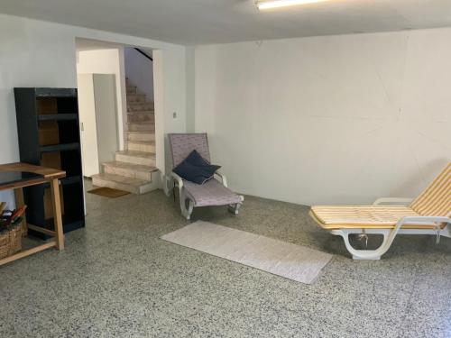a living room with two chairs and a bench and stairs at Cantinho alegre em Cascais in Cascais