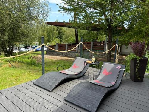 two chairs and a table on a wooden deck at rishko resort - Lake View - Private Sauna - free Parking - 24hr Self chceck-in in Holčíkovce